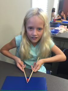 a student lifting hot tamales candy with chopsticks, using two hands