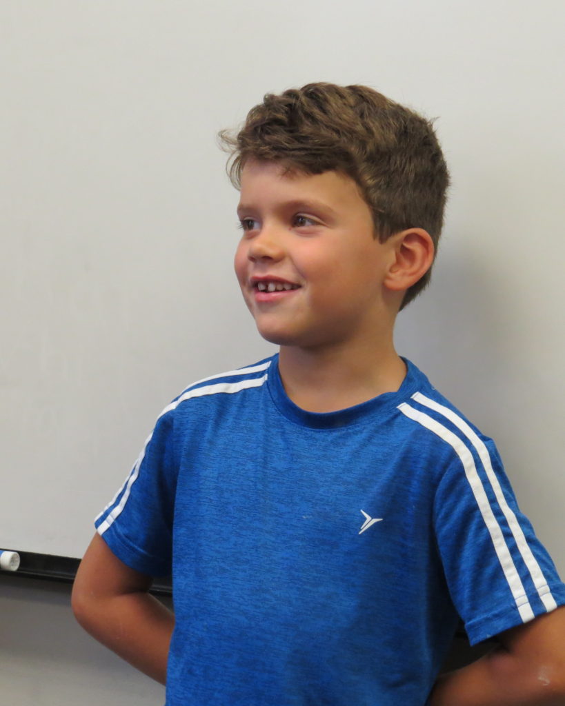 A boy telling personal narratives in front of a group of students.