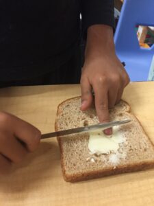 boy spreading butter on a slice of bread