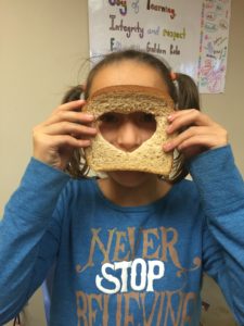 a girl holding up a piece of bread without the heart shaped middle