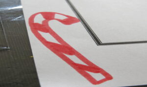 a candy cane drawn on paper with red marker