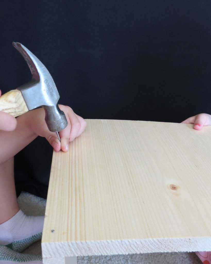a child hammering in a nail