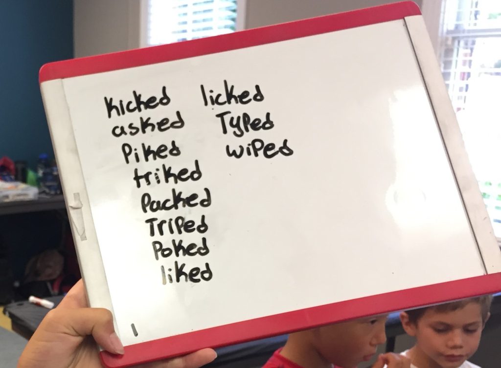 A child writes a list of past verbs that end in ED.
