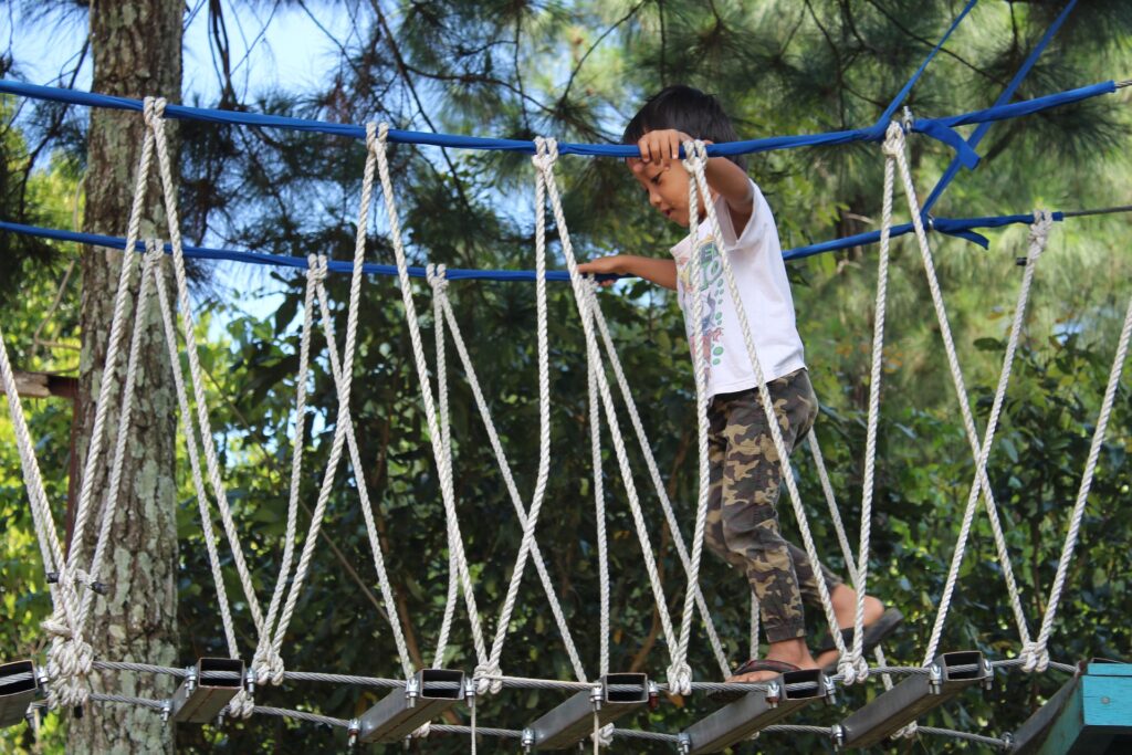 A boy walking across a rope bridge